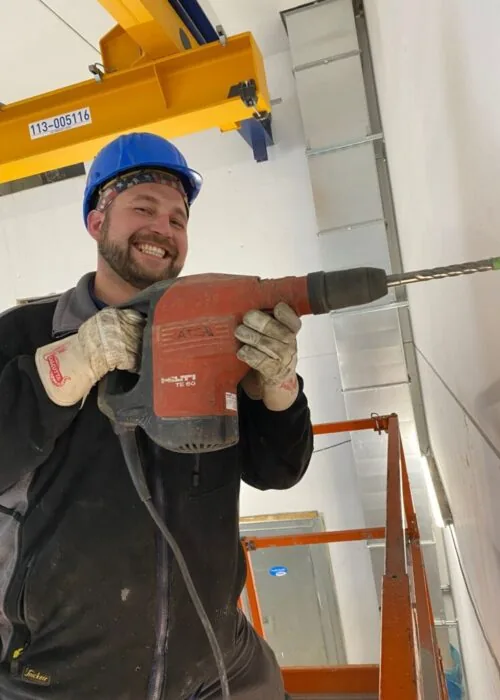 Bartosz Lewandowski mit Bohrhammer auf der Baustelle